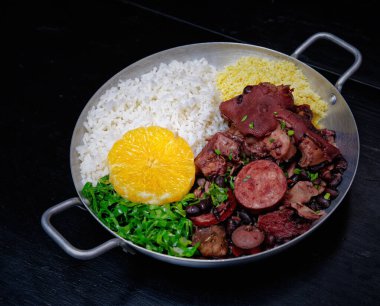 Sosis, lahana, pirinç ve portakallı Brezilya feijoadası.