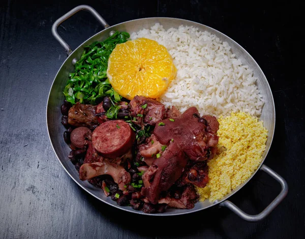 Sosis, lahana, pirinç ve portakallı Brezilya feijoadası.