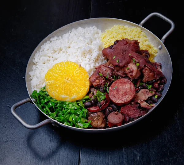 Sosis, lahana, pirinç ve portakallı Brezilya feijoadası.