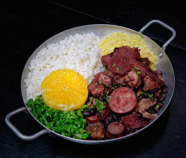 Sosis, lahana, pirinç ve portakallı Brezilya feijoadası.