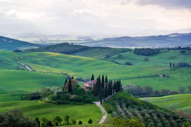 San Quirico d 'Orcia yakınlarındaki Orcia Vadisi' nin tepelerindeki çiftlik evleri ve villaları.