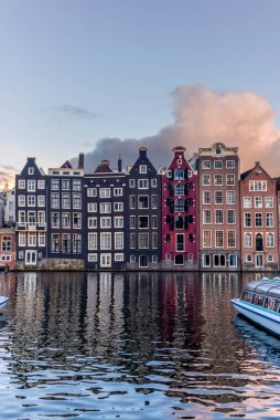Gün batımında Amsterdam 'daki Damrak Kanalı dans evleri manzarası