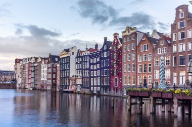 Gün batımında Amsterdam 'daki Damrak Kanalı dans evleri manzarası