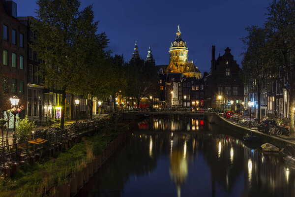 The Basilica of Saint Nicholas in Amsterdam reflecting in the waters of the Voorburgwal canal  at night