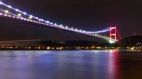 stock image The illuminated bridge on the Bosphorus strait late at night in Istanbul with light trails from the ships