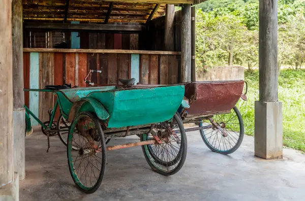 Kamboçya 'da Kampot' ta bir evin altına park edilmiş eski bisiklet triportörleri.