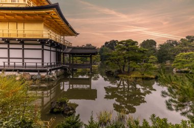 Kyoto 'daki Altın Pavyon sonbaharda göletin sakin sularını yansıtıyor.