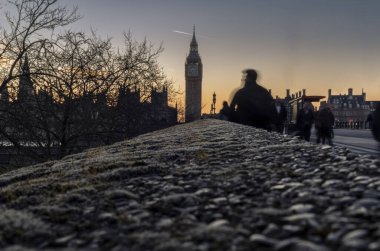 Londra 'daki Westminster Köprüsü' nde kasıtlı hareket bulanıklığı olan insanların siluetleri.