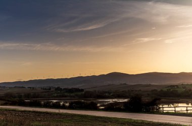 Tuscan kırsalındaki Santa Luce Gölü, tipik tepe ve ağaç manzarası ile renkli bir gündoğumu sırasında