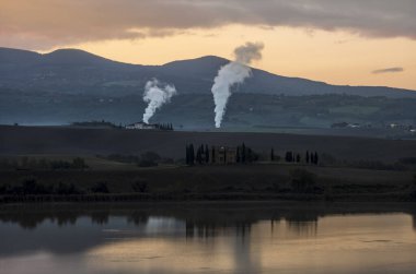 Tuscan kırsalındaki Santa Luce Gölü, tipik tepe ve ağaç manzarası ile renkli bir gündoğumu sırasında