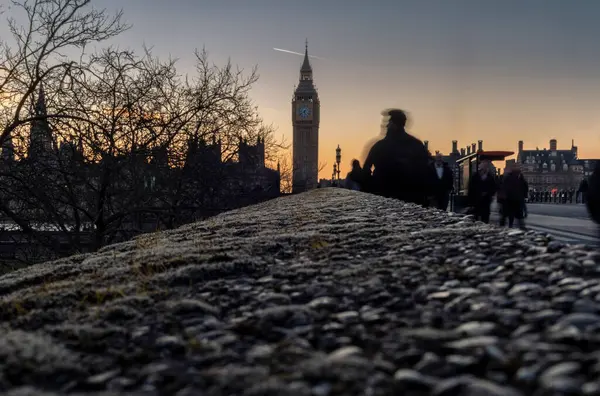 Londra 'daki Westminster Köprüsü' nde kasıtlı hareket bulanıklığı olan insanların siluetleri.