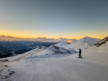 Yalnız bir snowboardcunun silueti sabahın erken saatlerinde İsviçre 'deki Lenzerheide Staetzerhorn tepesinden Alp Dağları' nda güneşin doğuşunu izliyor.