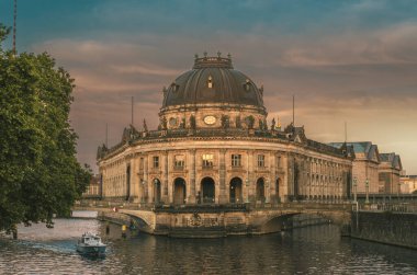 Gün batımında Berlin 'deki Müze Adası' nın önündeki Spree Nehri 'nde bir motorlu tekne.