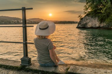 İsviçre 'de Lucerne Gölü' nde gün batımını izleyen uzun boylu bir kadın.