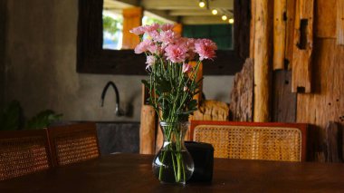 Ahşap Yemek Masasında Açık Cam vazoda Yumuşak Pembe Çiçek Düzenleme