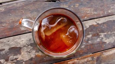 Bardakta buzlu çay, ahşap masada ferahlatıcı içecek.