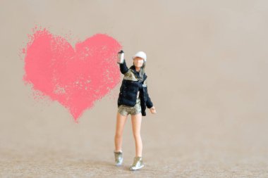 Miniature people, Artist holding dispenser and spraying with red heart shapes, Valentine day concept
