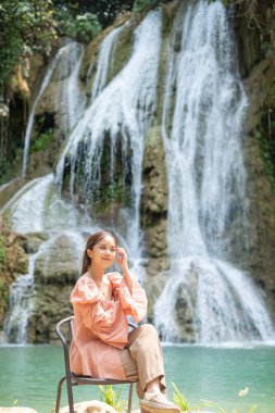 Lung Prabang, Laos 'taki Khoun Moung Keo Şelalesi' nin önünde oturan genç Asyalı kadın..