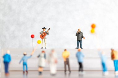 Minyatür insanlar. Şarkıcı ve müzisyen sahnede gitar çalıyor. Dünya müzik günü konsepti.