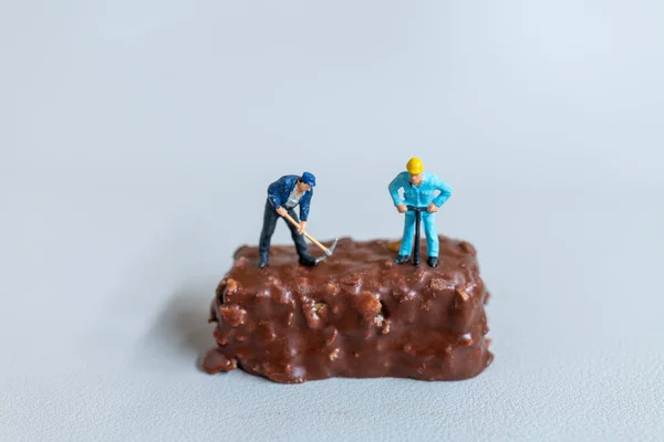 Miniaturmenschen Ein Mitarbeiter Fertigt Einen Schokoriegel Auf Grauem Hintergrund Konzept Stockbild