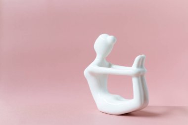 Yoga pozu veren seramik Yoga Kadın figürü, pembe arka planda Dhanurasana yaylı poz
