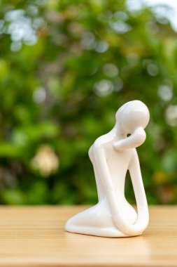 Seramik Yoga Kadın figürü ahşap zeminde yoga pozu veriyor ve yeşil yaprak arka planda