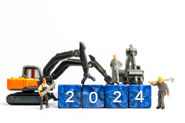 Minyatür insanlar, işçi takımı beyaz arka planda 2024 rakamıyla bir blok çeviriyor.