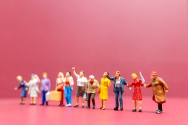 Minyatür insanlar, bir grup kadın, Uluslararası Kadınlar Günü 'nün pembe arka planında bir araya gelirler.