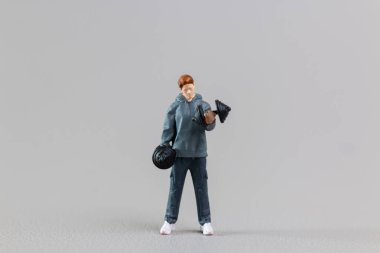 Minyatür insanlar, zinde genç adam gri zemine karşı ağırlık kaldırıyor.