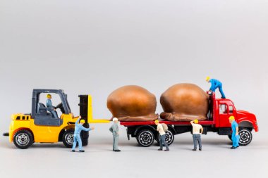 Minyatür insanlar, işçi takımı çikolata topunu gri arka planda taşıyorlar. Çikolata günü konsepti.