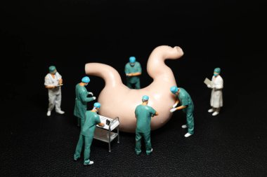 Önlüklü minyatür cerrahlar insan midesinin büyük bir modelini ameliyat ediyorlar. Sağlık ve Tıbbi Konseptler