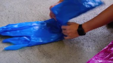 Geri dönüşüm ve çevre dostu uygulamaları vurgulayarak, büyük mavi bir poşeti düzgünce katlayan ellerin yakın çekimi