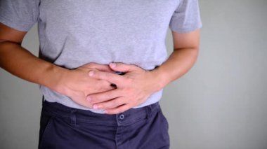 Karnını tutan bir adamın, mide ağrısı ya da rahatsızlığını gösteren yakın çekim görüntüleri. Sağlık ve sağlık konularında hazımsızlık ya da sindirim sorunları gibi belirtileri gösteren