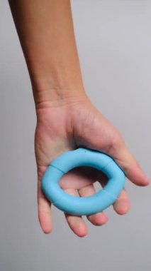 Mavi silikon yüzüğü tutan bir elin yakından görüntüsü, el gücü eğitimi, stres atma ve kas tonlaması için ideal. Sağlık, zindelik ve refah içeriği için harika stok görüntüleri.