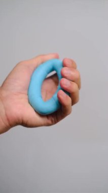 Mavi silikon yüzüğü tutan bir elin yakından görüntüsü, el gücü eğitimi, stres atma ve kas tonlaması için ideal. Sağlık, zindelik ve refah içeriği için harika stok görüntüleri.