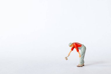 Kırmızı gömlekli bir ressamın minyatür figürü, beyaz arka planda fırçayla resim yapar gibi öne eğiliyor.