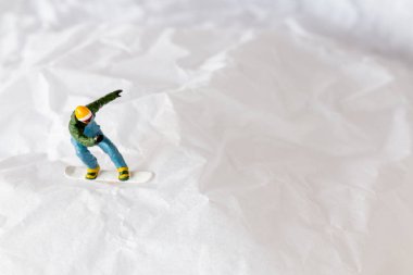 Minyatür insanlar, canlı kış giysileri içinde kar yamacını oyan snowboardcular. Kış sporları ve macera için ideal