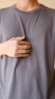 Göğsünü tutan bir kişi, genellikle asit reflüsü veya mide ekşimesiyle ilişkili rahatsızlığı gösterir.