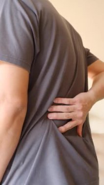 Sırtını sımsıkı tutan biri, acı ya da zorlanma belirtisi gösterir. Bu görsel, sırt ağrısı kas yorgunluğunu temsil ediyor.