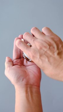 Kapsülleri kahverengi bir ilaç şişesinden palmiyeye döken ellerin yakın plan çekimi.