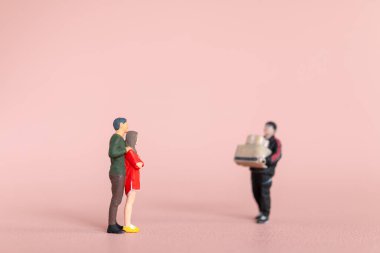 Minyatür biblo sahnesinde bir adam bir çifte hediyeler taşıyordu. Kadın şaşırmış görünüyordu. Sevgililer Günü konsepti.