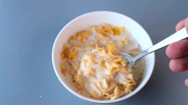 Bir kaşığın yakın plan çekimi bir kaseden taze süte batırılmış altın mısır gevreğini kaldırıyor. Yemek, sağlık ve yaşam tarzı kavramları için mükemmel.