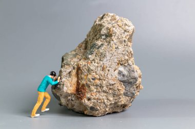 Büyük bir kayayı iten, azim, mücadele ve kararlılığı simgeleyen minicik bir adam figürü..