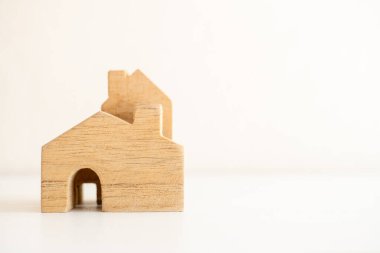 Minimalist ahşap ev modeli, konut, finans veya mimari tasarım temaları için ideal beyaz bir yüzeye yerleştirilmiştir..