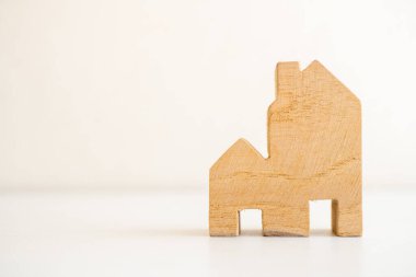 Minimalist ahşap ev modeli, konut, finans veya mimari tasarım temaları için ideal beyaz bir yüzeye yerleştirilmiştir..