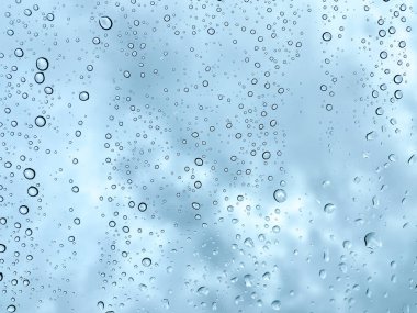 Camdaki yağmur damlaları karanlık, bulutlu gökyüzüne karşı barışçıl ve atmosferik
