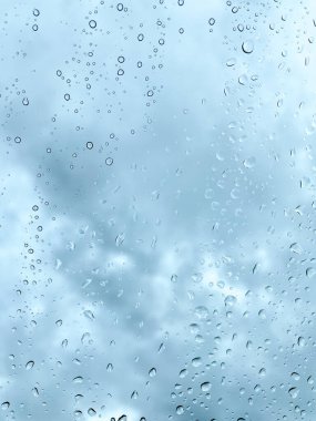 Camdaki yağmur damlaları karanlık, bulutlu gökyüzüne karşı barışçıl ve atmosferik