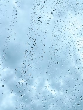 Camdaki yağmur damlaları karanlık, bulutlu gökyüzüne karşı barışçıl ve atmosferik