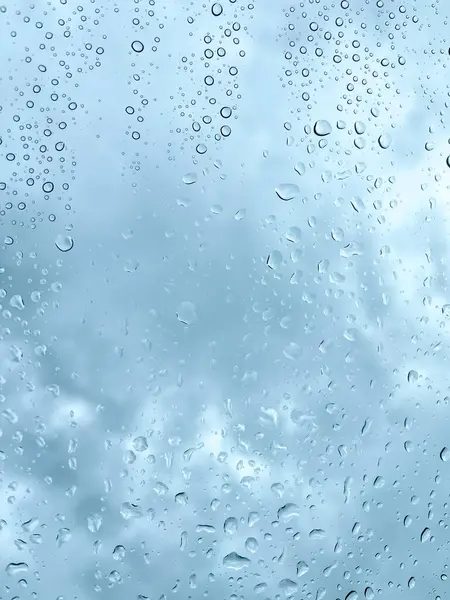 Camdaki yağmur damlaları karanlık, bulutlu gökyüzüne karşı barışçıl ve atmosferik