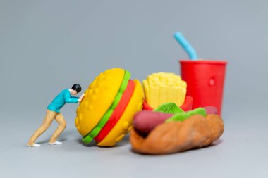 Dev Fast Food 'u iten minyatür figür bu neşeli sahne mizahi bir şekilde diyet, aşırı tüketim ve çaba temaları vurguluyor.